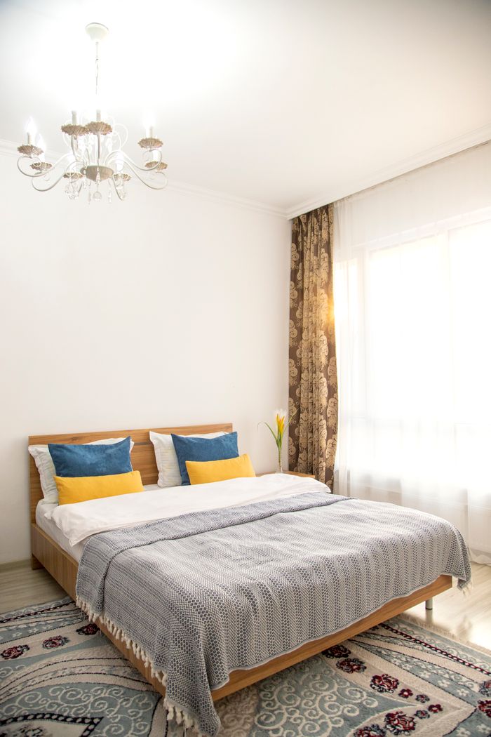 Warm and inviting bedroom with elegant chandelier and stylish bedding, perfect for relaxation.