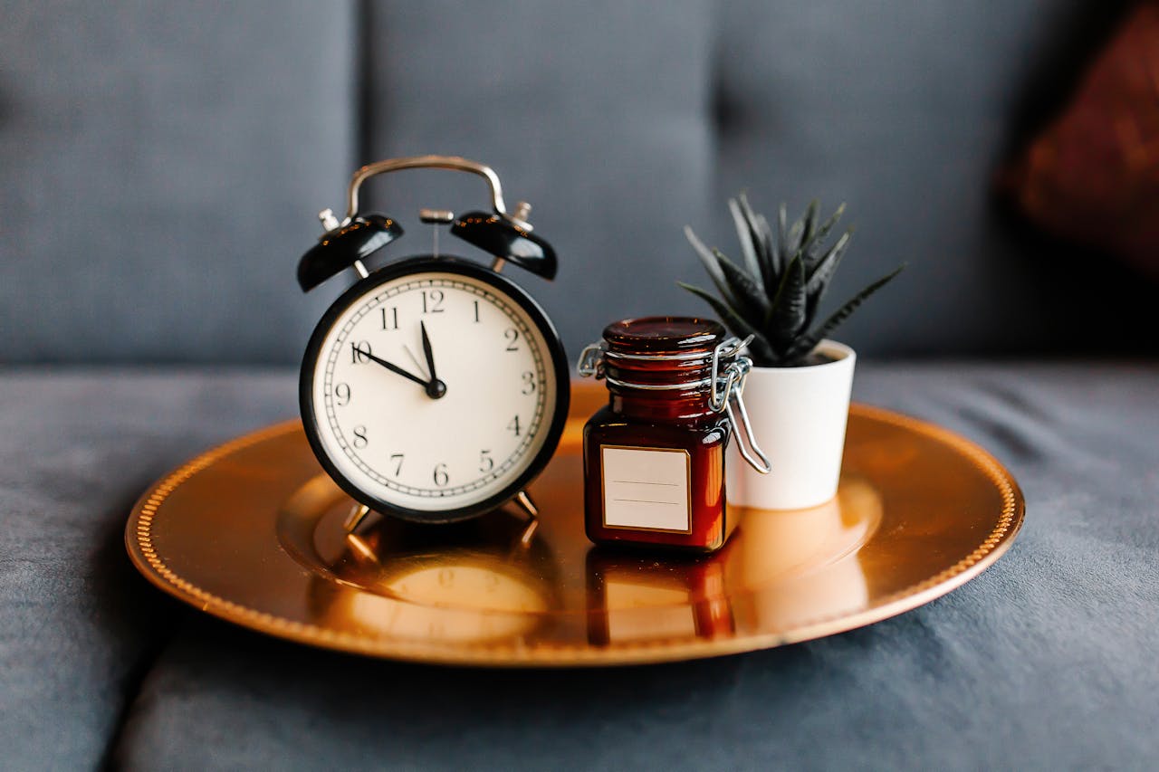 Mastering the First Impression: Your intriguing post title goes here Aesthetic arrangement of a clock and jar on a golden tray with a potted plant.